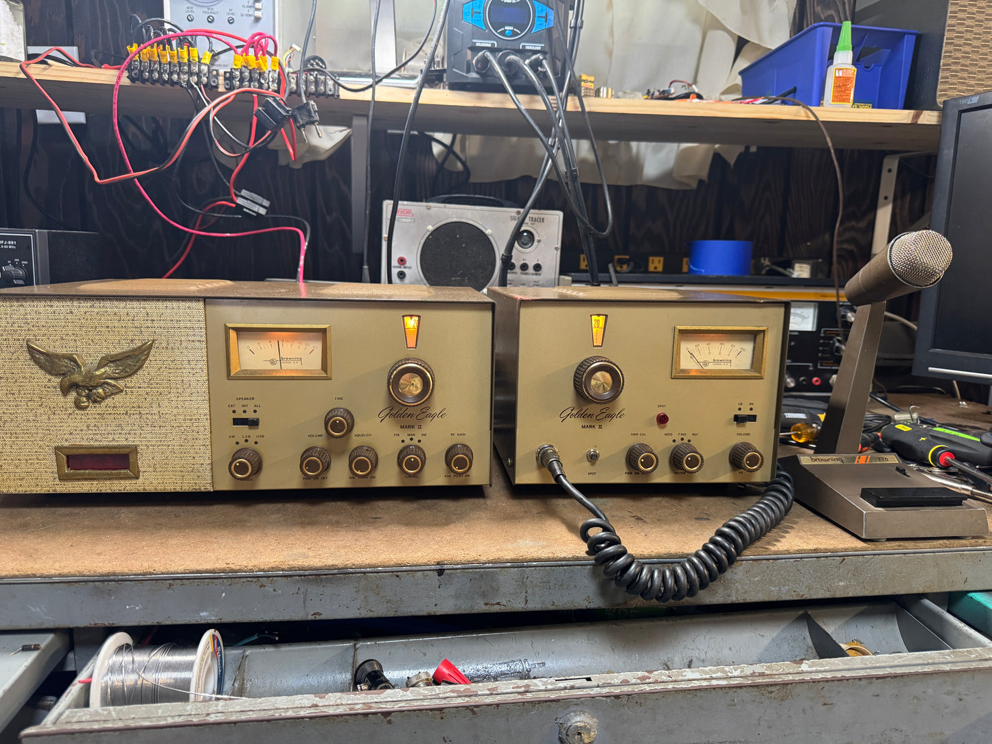Vintage electronic equipment on a workbench with various tools and wires in the background.