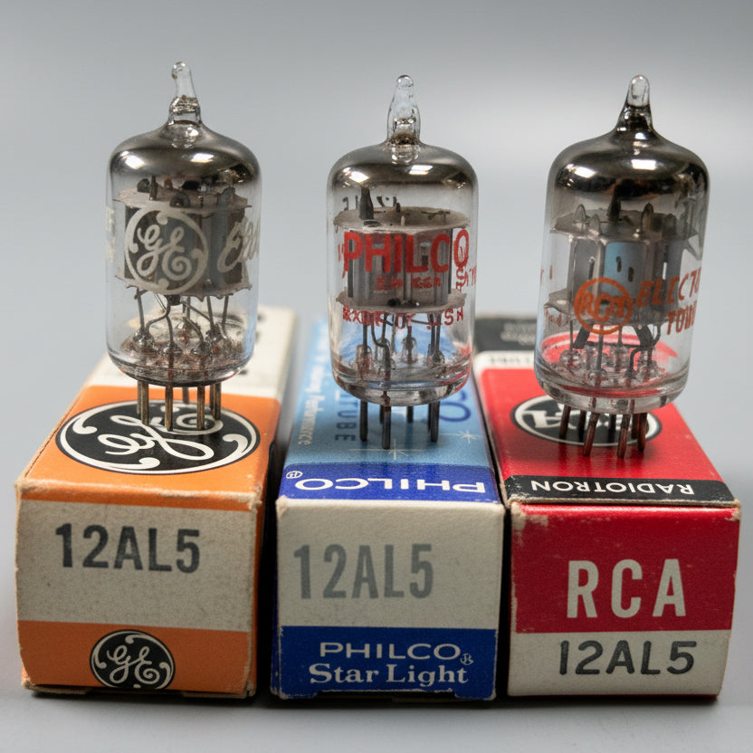 Three vacuum tubes on their original boxes with brand labels on a blue fabric background