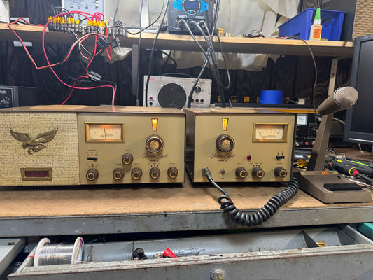 Vintage electronic equipment on a workbench with various tools and wires in the background.