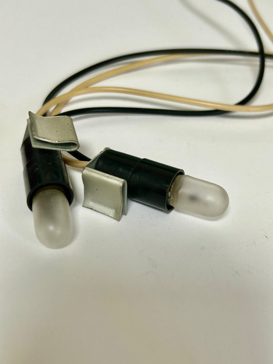 Two light bulbs with metal clips and wires on a white background