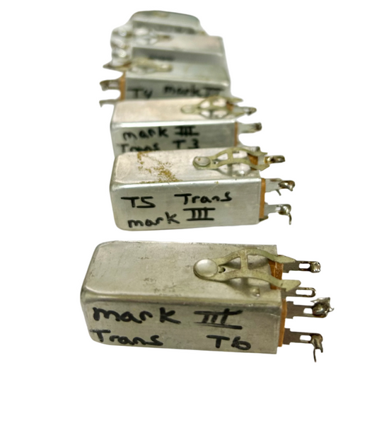 Row of metallic components with handwritten labels on a white surface