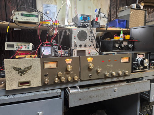 Vintage electronic equipment on a workbench with wires and tools.