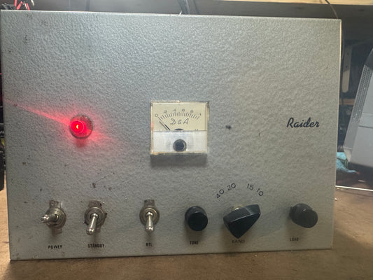 Vintage electronic device with a red light and control knobs on a metallic surface.