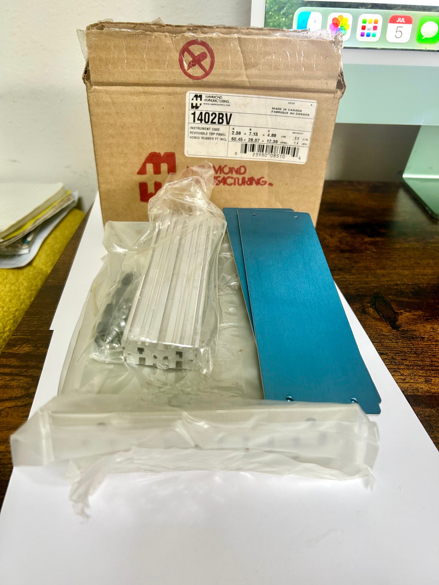 Packaged metal components on a white surface with a cardboard box in the background