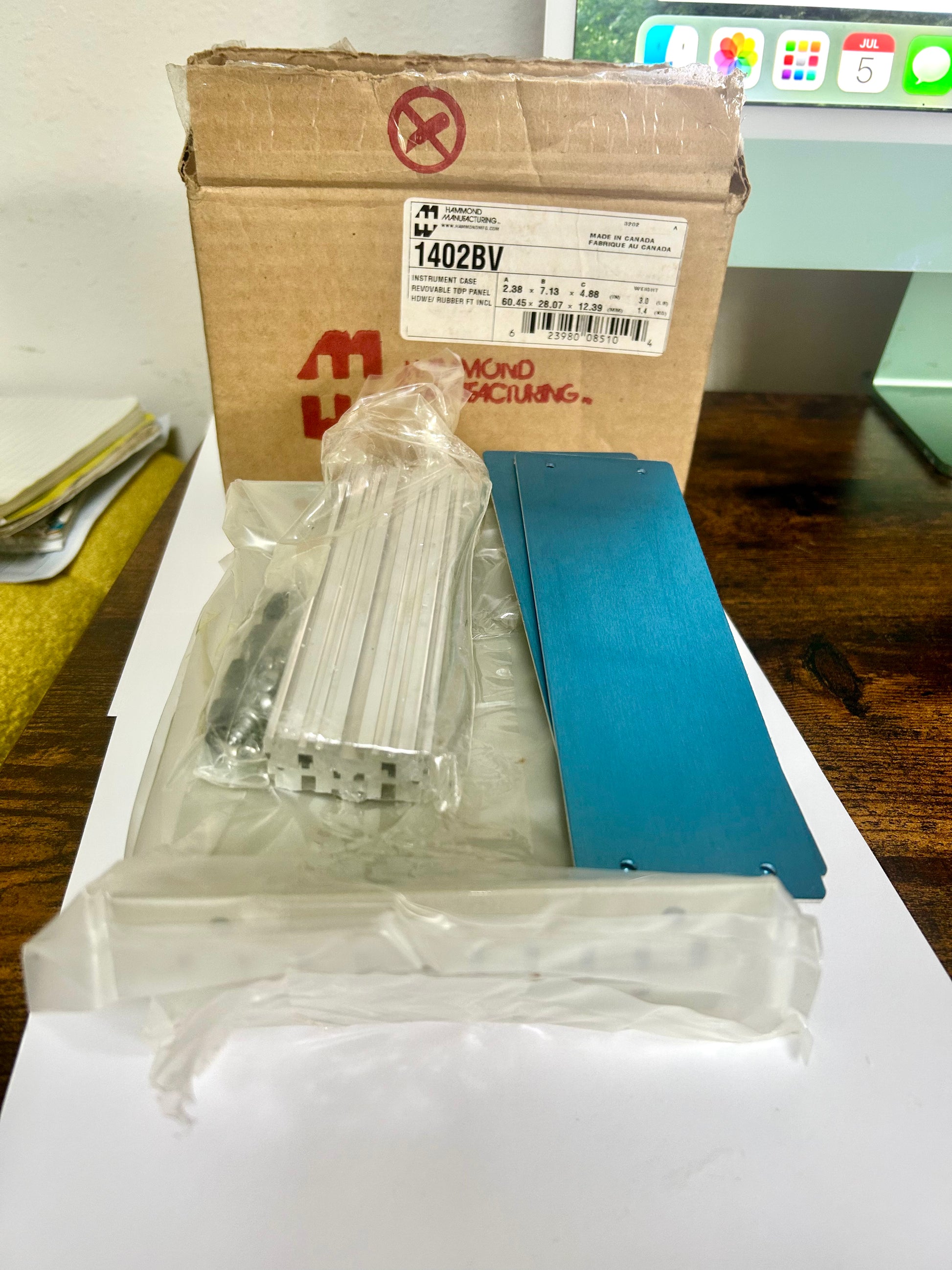 Packaged metal components on a white surface with a cardboard box in the background