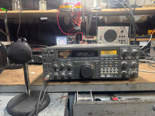 Radio receiver on a workbench with various equipment in the background